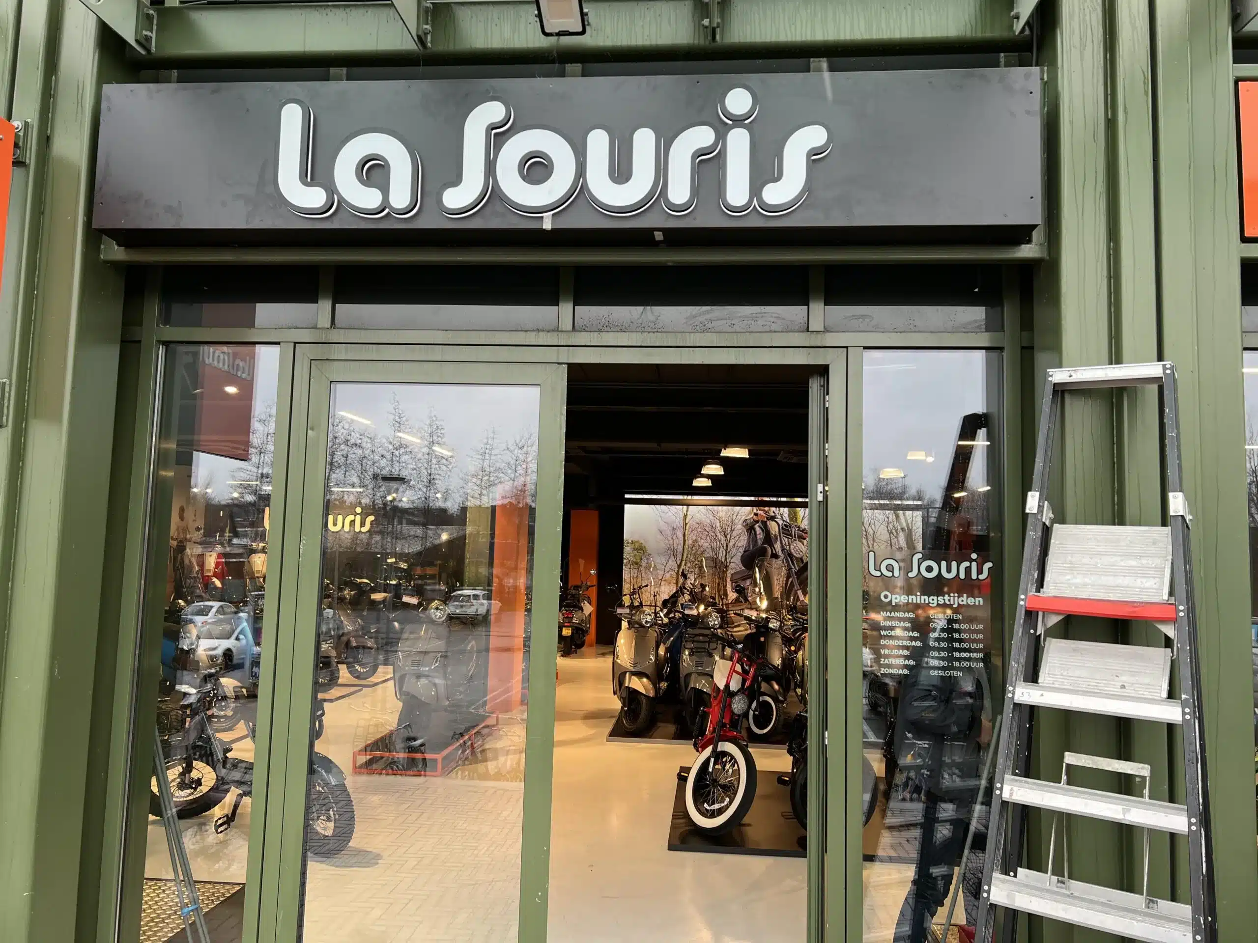 Winkelpui van een scooterwinkel met een ladder in de deuropening tijdens de werkzaamheden